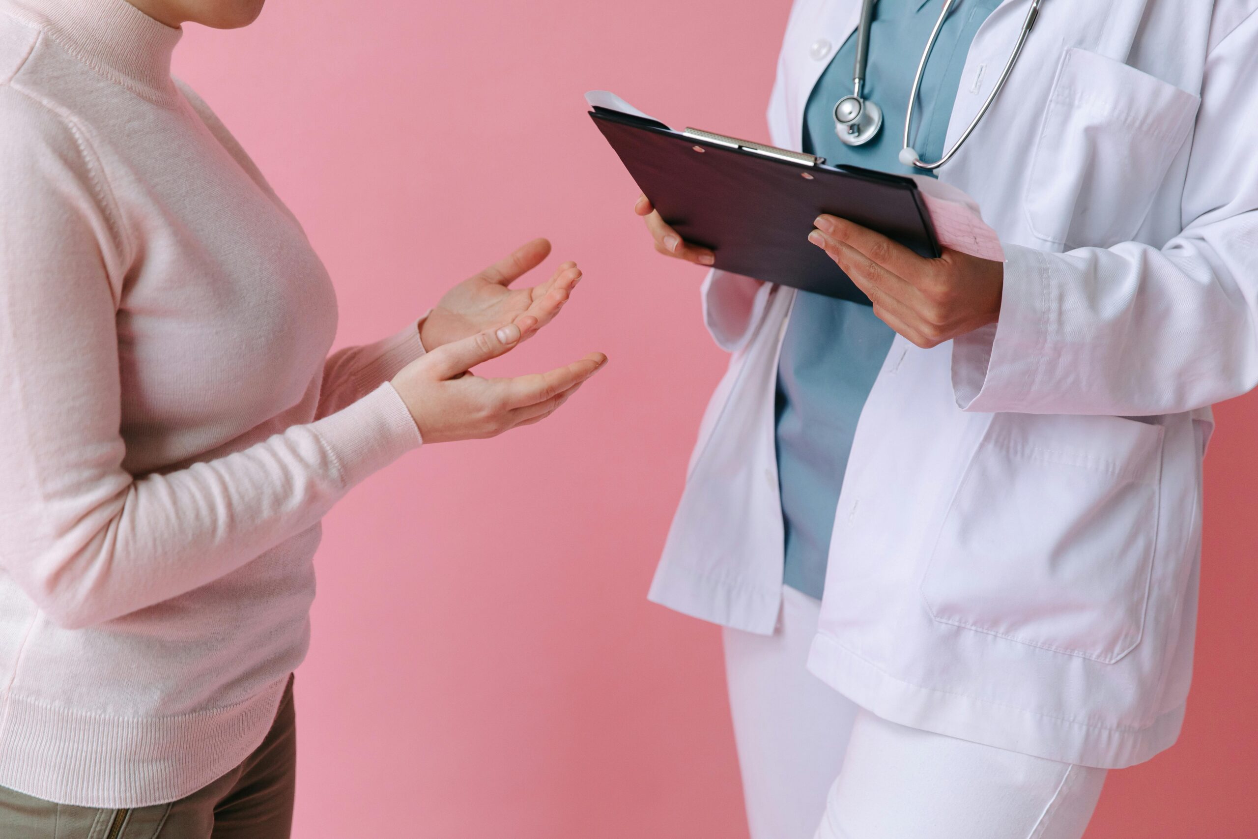 Close-up of a patient and a doctor talking, with a clipboard in their hand