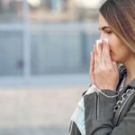 woman holding a tissue to her nose