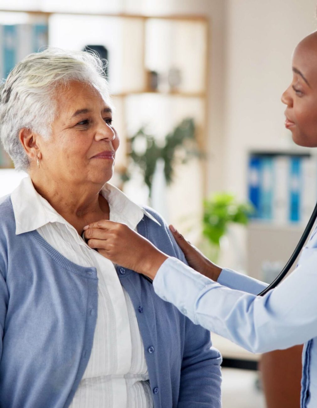 Woman, doctor and senior person with stethoscope, checkup or medical advice at clinic consultation. Help, healthcare and elderly patient in office with lung test, heart beat or chest exam in hospital.