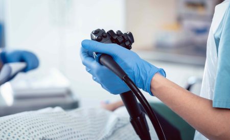 Close up of gloved hand holding a colonoscopy tool