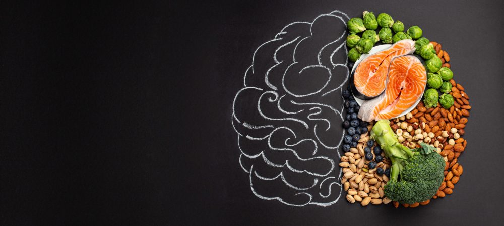 Chalk hand drawn brain picture with assorted food, food for brain health and good memory: fresh salmon, vegetables, nuts, berries on black background. Foods to boost brain power, top view, copy space
