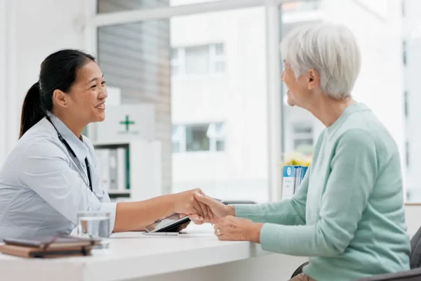 Doctor handshake, senior woman and healthcare with thank you in a hospital for medical care. Elderly consultation, smile and insurance conversation with women in a clinic office for retirement advice.